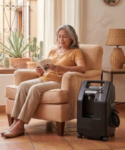 Concentrador de oxígeno DeVilbiss 525DS de 5 litros en uso doméstico junto a un sillón