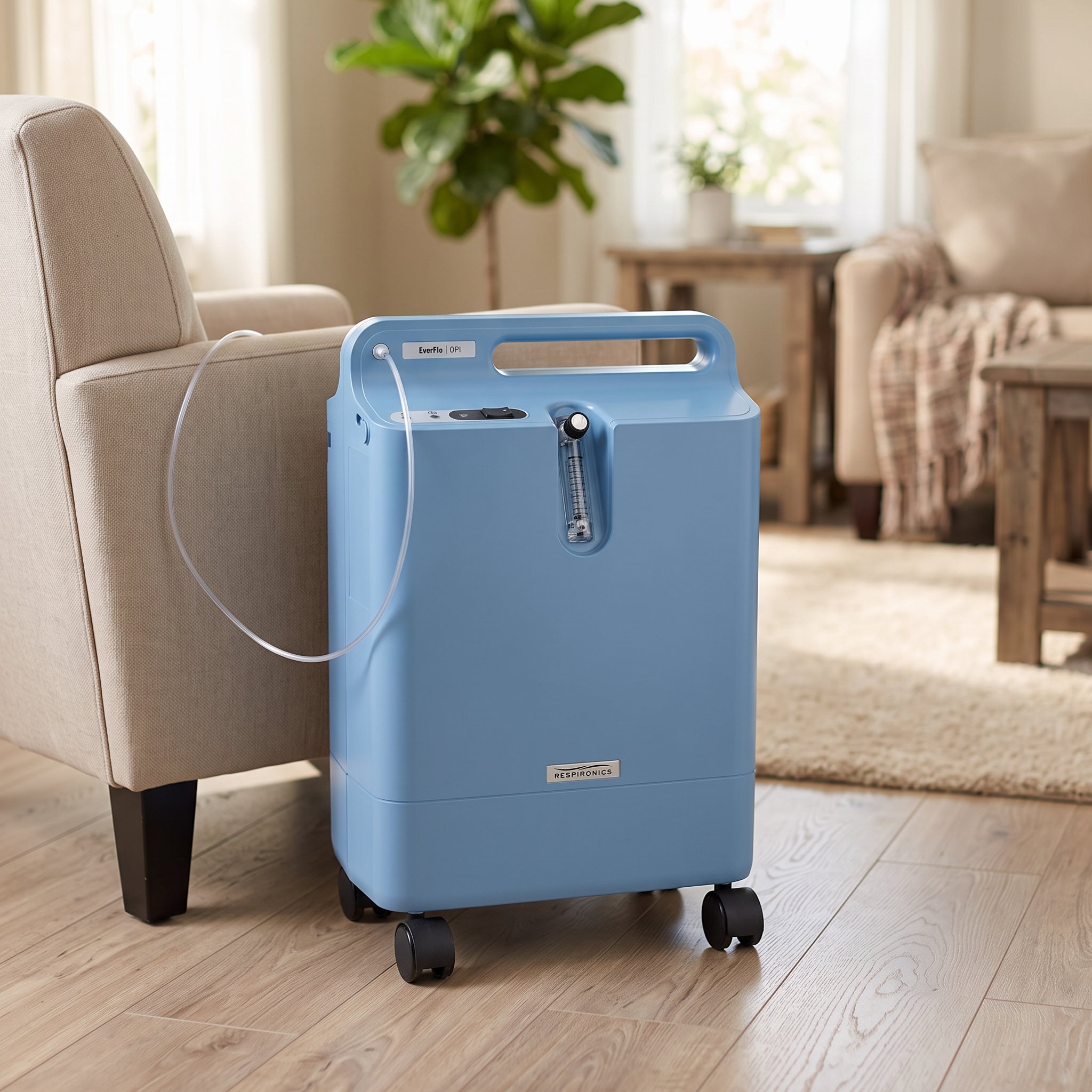 Concentrador de oxígeno Philips Respironics EverFlo OPI instalado en una sala de estar, con cánula nasal junto a un sillón, en un ambiente hogareño tranquilo