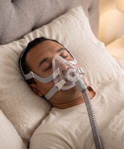 Hombre durmiendo tranquilamente con la mascarilla CPAP de cara completa ResMed AirFit F20 puesta y conectada al tubo