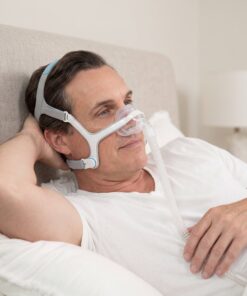 Hombre adulto usando la mascarilla nasal CPAP ResMed AirFit N20 mientras descansa cómodamente